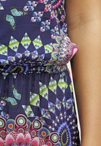 Vestido multicolorido con patrones geométricos, mariposas y diseños florales. Hecho de tela ligera con una cinturilla elástica.