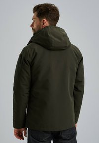 Donkergroene, gewatteerde jas met een gladde textuur, voorzien van een ritssluiting en subtiele stikdetails, gezien vanuit de achterkant.