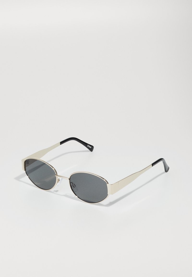 Sunglasses with oval gray lenses, silver metal frame, and black accents on temples. Features a sleek design and minimal hardware.