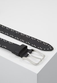 Cinturón de cuero negro con tachuelas plateadas, hebilla rectangular de metal plateado y superficie texturizada. Con agujeros para ajustar el tamaño.