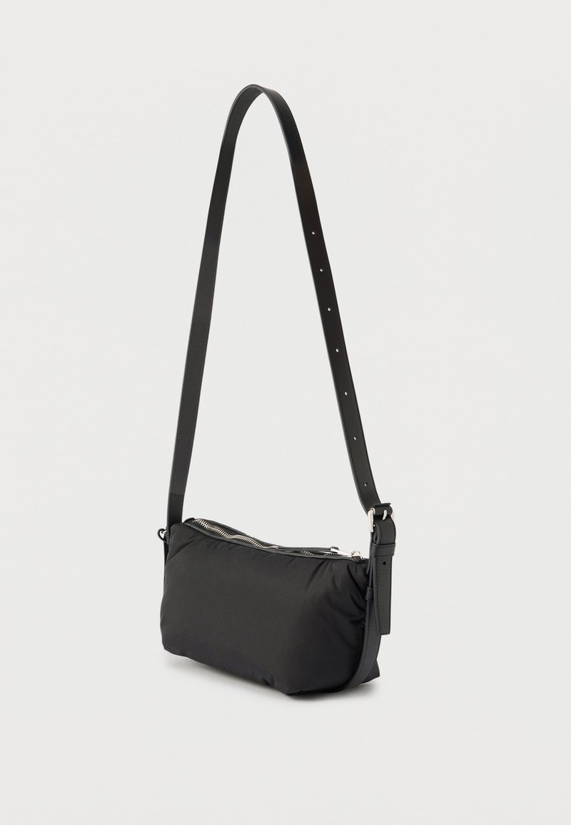 Sac à épaule noir avec bandoulière ajustable et fermeture éclair, présenté sur un fond clair uni.