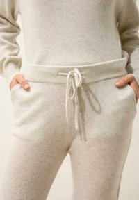 Ljust gråa loungebyxor i mjukt tyg, med dragsko i midjan, fickor och en lätt textur för extra detalj.