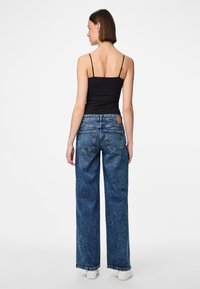 Aukštai juosmeniai, platūs džinsai iš išblukusio mėlyno džinsinio audinio, turintys penkis kišenes ir odinį ženkliuką ant nugaros juosmens.