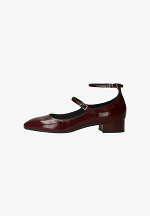 Burgundy patent leather flats with a pointed toe, adjustable ankle strap, and a low block heel. Smooth texture and sleek design.