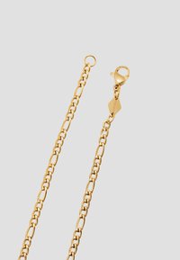 Guldkæde med ovale led, udstyret med en kroglås og en logo-graveret mærkat for ekstra detaljer. Glat, skinnende tekstur.