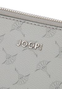 Jasnoszary portfel o fakturowanej powierzchni z subtelnym logo "JOOP!", srebrnym zamkiem błyskawicznym i tłoczonym motywem kwiatowym.