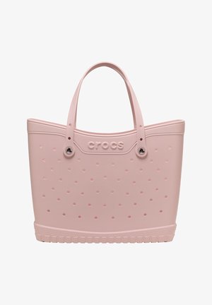 Hellrosa Crocs Tragetasche mit perforierten Löchern, doppelten Griffen und einer strukturierten Basis für das Tragen und den Freizeitgebrauch.