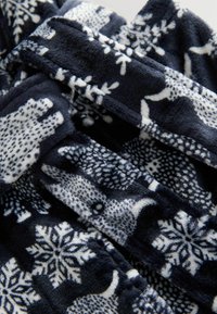 Mörkblå fleece-tyg med ett mönster av vita isbjörnar och snöflingor, mjuk textur och oregelbundna former.