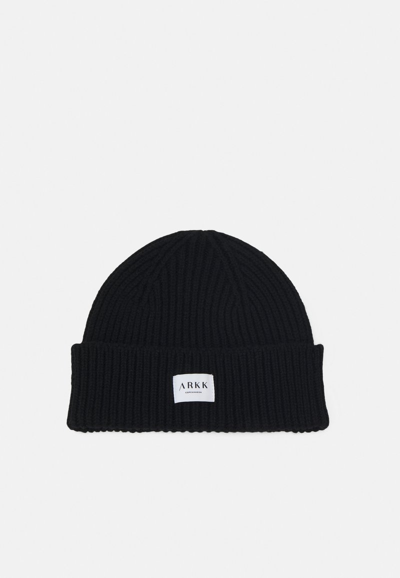 Black knit beanie with a ribbed texture and a folded cuff. Features a small white label with the brand name "ARKK" attached to the front.