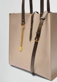 Borsa tote in ecopelle beige con manici marroni, dettaglio in catena dorata e logo in rilievo. Forma rettangolare con design minimalista.