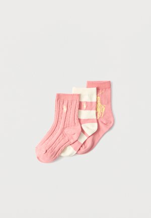 Tre børnesokker i pink og hvid, en helt pink, en med striber i pink og hvid, og en pink med en gul rytterlogo.