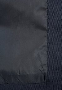 Tela negra con una textura suave, que presenta un patrón diagonal y una sección sólida. Sin accesorios ni herrajes visibles.