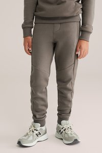 Grå sweatpants med ett strukturerat mönster, smal passform, ankelslut och sidoseamdetaljer, bärs med ljusgrå löparskor.
