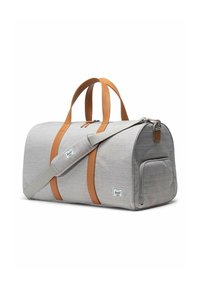 Sac de voyage en tissu gris avec des poignées et des accents en cuir marron. Dispose d'une bandoulière et d'une poche à fermeture éclair à l'avant. Couture renforcée visible.