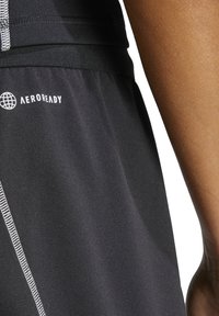 Zwarte sportshorts met AEROREADY merk, gemaakt van gladde stof, met reflecterende stiksels en een elastische tailleband voor comfort.