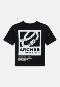 Μαύρο μπλουζάκι με λευκό γραφικό σχέδιο σχοινιού αναρρίχησης, κείμενο "ARCHES HIKES & more" και πληροφορίες τοποθεσίας τυπωμένες στην πλάτη.