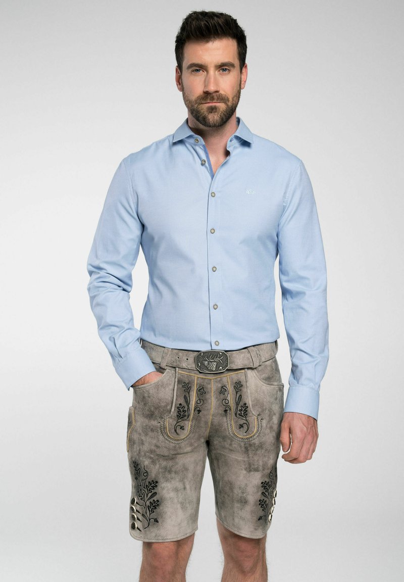 Chemise bleu clair à manches longues. Lederhose gris avec broderies noires et une ceinture décorative. Style décontracté et traditionnel.