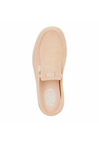 Chaussure slip-on beige clair avec une tige en daim lisse, un col rembourré et une semelle en caoutchouc texturée. Elle présente une étiquette de marque et un design minimaliste.