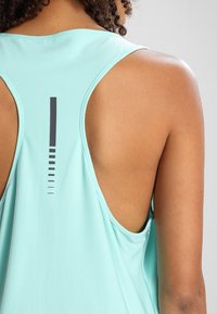 Jasnoniebieska sportowa koszulka bez rękawów z wycięciem typu racerback, z pionową czarną linią i stopniowanymi kropkowymi akcentami na plecach.