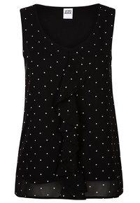 Blusa sin mangas negra con lunares blancos, que presenta un escote en forma de V, un frente con volantes y un dobladillo inferior semi-transparente. Hecha de una tela ligera.