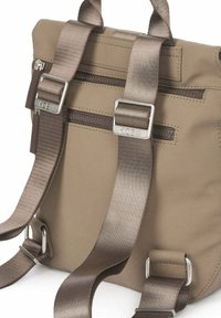 Mochila beige con correas anchas de satén ajustables, hebillas metálicas y asa superior, con bolsillo horizontal con cremallera en el panel trasero.