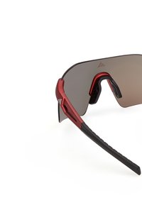 Gafas de sol deportivas con lentes grandes y oscuras, montura roja y terminales de varilla de goma negra sobre un fondo blanco.