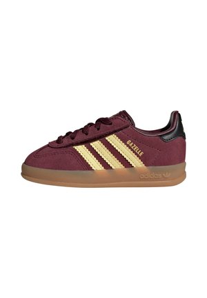 Bordowe buty sportowe Adidas Gazelle z beżowymi paskami, gumową podeszwą, czarną zakładką na pięcie i złotym napisem "GAZELLE" po boku.