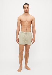 Μπεζ μαγιό σορτς με κορδόνι στη μέση, φτιαγμένα από ελαφρύ υλικό, με απλό σχέδιο και μήκος πάνω από το γόνατο.