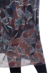 Genomskinlig meshkjol med abstrakta mönster i flera färger, med en mörk bakgrund och röda, blåa och gröna accenter. Flödande design.