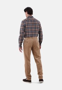 Braune Cordhosen und ein karierter Hemd in Blau-, Braun- und Grautönen, von hinten betrachtet, mit Gesäßtaschen und langen Ärmeln.