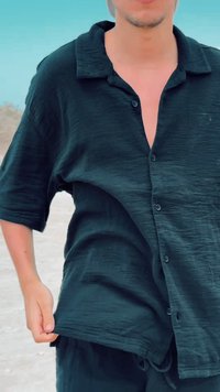 Czarna koszula z krótkim rękawem na guziki z teksturowanej tkaniny. Posiada luźny krój i głęboki dekolt w kształcie litery V, z pięcioma widocznymi guzikami z przodu.