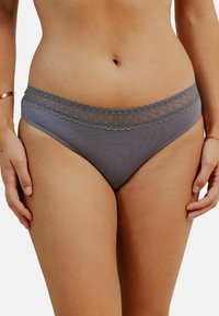 String en coton gris mélangé avec un tissu doux, bordé de dentelle autour de la taille, offrant une texture lisse et une coupe classique.
