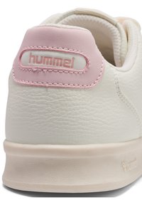 Obcas białego skórzanego buta sportowego z teksturowaną powierzchnią, różowym akcentem na górze oraz logo w różowym haftowaniu z tyłu.