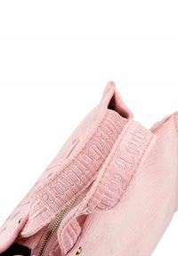 Borsa in corduroy rosa con tracolla ricamata e una cerniera dorata parzialmente visibile su sfondo bianco.