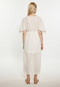 Lichtgewicht, crème-kleurige maxi-jurk met een openwork ontwerp, korte uitlopende mouwen en kwastjesafwerking aan de zoom.