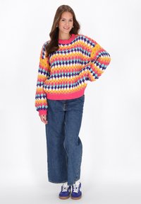 Bunter gestrickter Pullover mit einem Rautenmuster in verschiedenen Gelb-, Pink-, Blau- und Lilatönen, mit einem gerippten pinken Halsausschnitt und Bündchen.