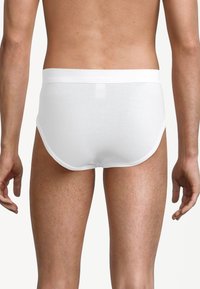 Pantaloni intimi bianchi in cotone con un morbido elastico in vita, caratterizzati da una superficie liscia e un design aderente, che mostrano il retro di un modello maschile.