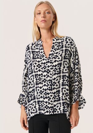 Blusa black and white a fantasia con scollatura a V, maniche lunghe e polsini arricciati; realizzata in tessuto leggero con finitura testurizzata.