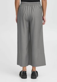 Grijze wijde broek met elastische tailleband, een gladde textuur en een casual pasvorm, gecombineerd met zwarte plateau schoenen.
