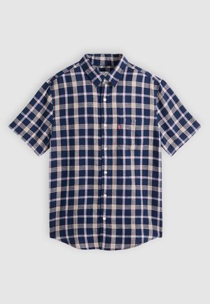 Πουκάμισο με κοντά μανίκια και κουμπιά, με καρό σχέδιο σε ναυτικό μπλε, λευκό και κόκκινο, με τσέπη στο στήθος, σε ανοιχτό γκρι φόντο.