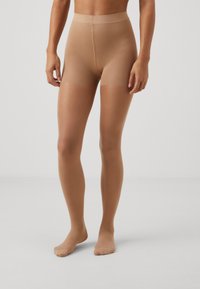 Beige transparente strømpebukser med høj talje, glat tekstur og lukkede tæer. Designet til at give et tætsiddende udseende på benene.