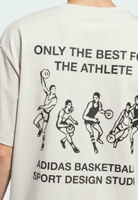 White cotton t-shirt featuring a back graphic with black illustrations of basketball players and bold text stating "ONLY THE BEST FOR THE ATHLETE."