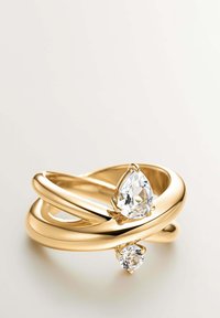 Anillo de banda retorcida de oro con una gema clara en forma de pera y otra redonda en cada extremo, sobre un fondo claro.