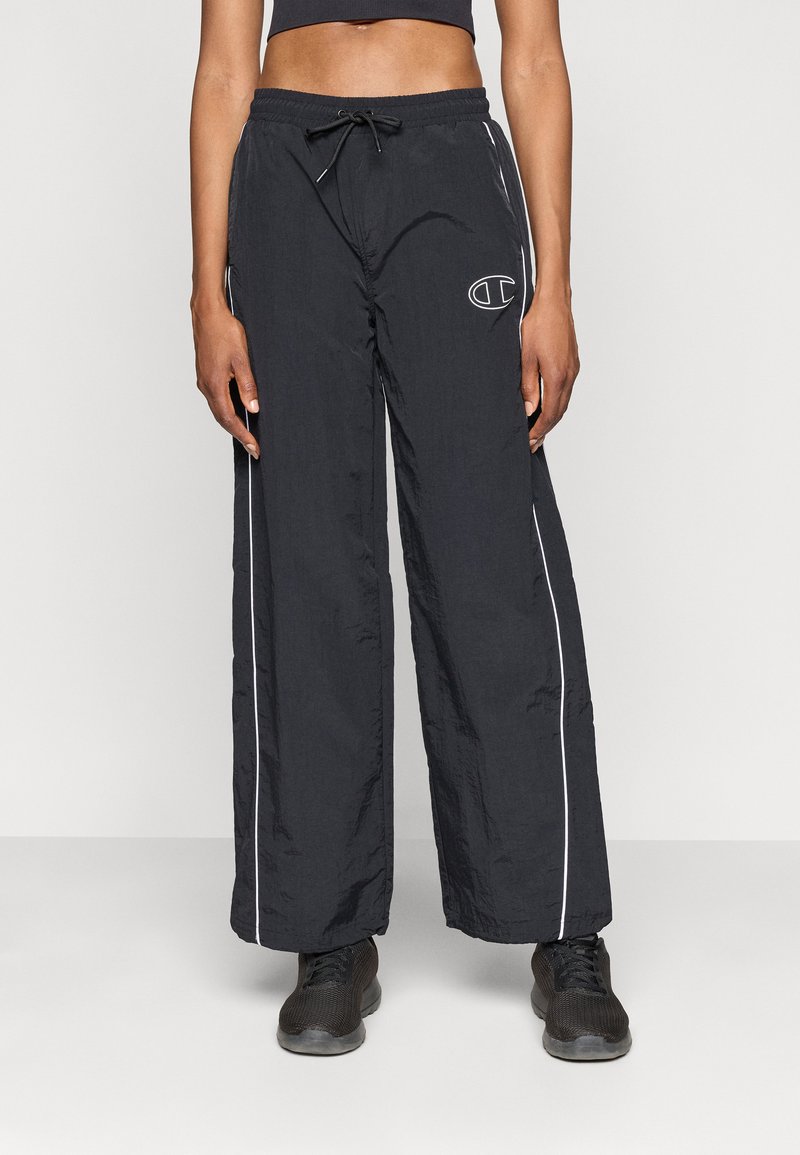Crne oversized hlače izrađene od lagane tkanine, s pojasom na vezanje i bijelim bočnim prugama, s logotipom na lijevom butu.