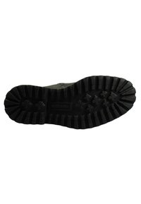 Semelle de chaussure en caoutchouc noire avec des motifs circulaires et des crans profonds. Présente une texture lisse et durable ainsi qu'un logo de marque bien en vue au centre.