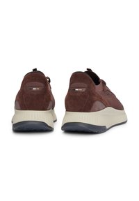 Baskets en suède marron avec des panneaux en maille texturée, avec une semelle crème et une semelle extérieure en caoutchouc foncé. Accents de logo distincts sur le talon.