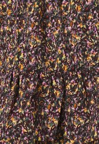 Blumenmusterstoff mit lebendigen Farben – lila, orange, grün – auf einem dunklen Hintergrund mit geraffter Textur und einem rüschierten Saum.