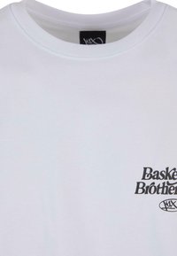 Hvid bomulds T-shirt med rund halsudskæring, der har sort trykt tekst "Basket Brothers" og et cirkulært logo detaljeret nederst til venstre.