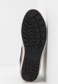 Černá gumová podrážka boty s texturovaným vzorem, s krémovým okrajem; značka "Tom Tailor Denim" a velikost "41" jsou viditelné.