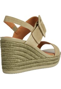 Sandalias de cuña beige de ante con una suela de cuerda texturizada. Presenta una correa ancha con una hebilla cuadrada y un diseño de punta abierta.